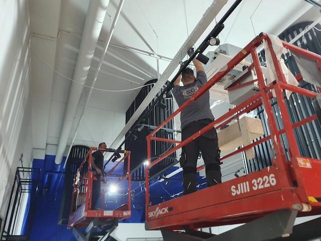 Monteur van Schouten Coolsupport op een hoogwerker hangt een installatie op in een hoge bedrijfshal